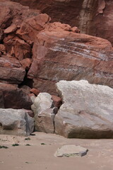 Naklejka premium Crumbled Red Rocks Sliding onto Sandy English Beach