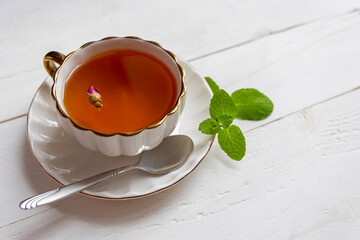 Cup of herbal tea with mint leaves. Elegant white teacup filled with herbal tea, garnished with a...