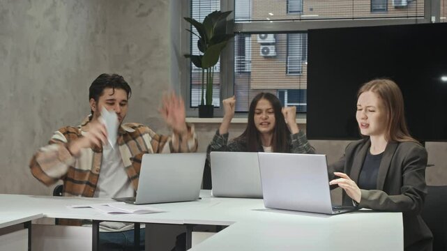Young office workers, eagerly following open of their project online, feel great sense of excitement and happiness. After start, they launch paper airplanes in various directions, celebrating their
