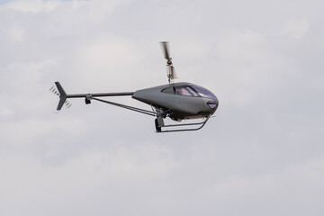 Modern gray two-seater small helicopter flying in the air