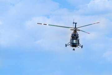 An old Soviet-designed black helicopter flies in the clear sky