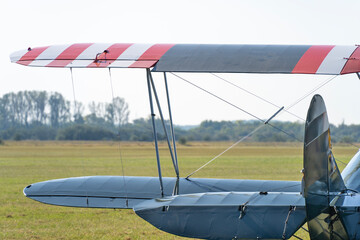 Close-up of the tail and wings of a green biplane on a grassy airfield