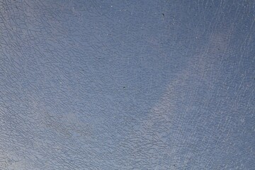 Broken glass in focus with diffuse blue-sky background.