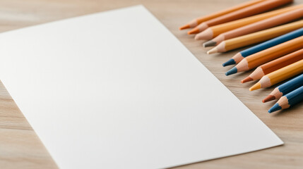 Obraz premium Artistic composition of colored pencils arranged beside a blank sheet on a wooden surface for creative projects and artistic expression