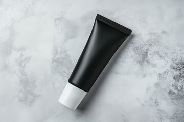 Flat black cosmetic tube on a light textured background. Minimalist skincare and product branding concept.