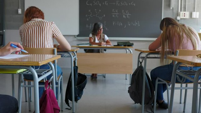Young teenage boy giving cheat sheet to classmate during examination in classroom. College students cheating on an exam. Focus on students hands. Education lifestyle concept.