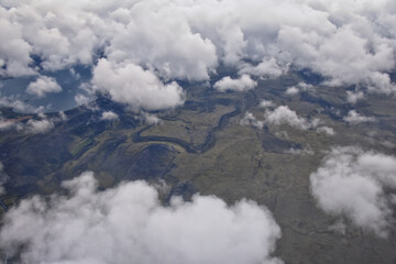 Iceland from airplane through clouds. Aerial scenic view of Iceland landscape. Travel vacation concept. Europe.