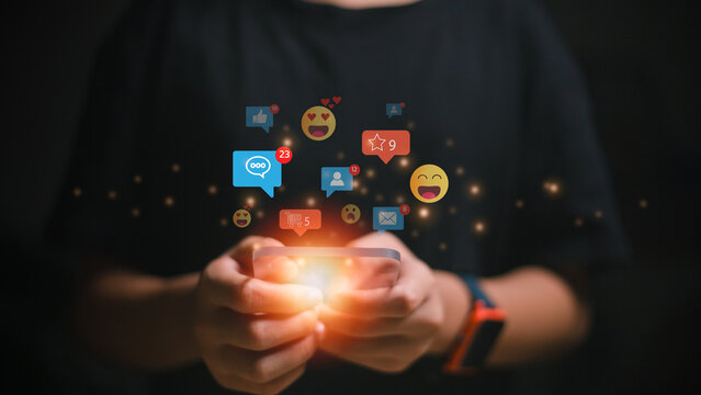 A man is using his smartphone with Social media. Social media and digital online concepts, online marketing, technology, chat, post, like, and follow are displayed on a futuristic phone screen.