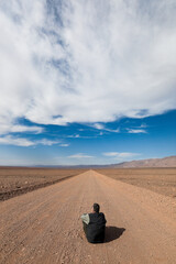 Desierto de Atacama. Una persona sentada en un camino polvoriento y solitario.