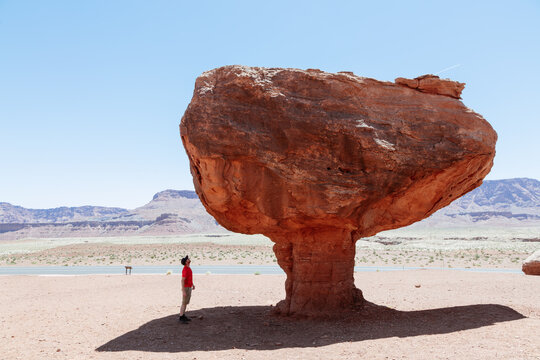 Man standing under big balancing rock in the desert, Utah, United States