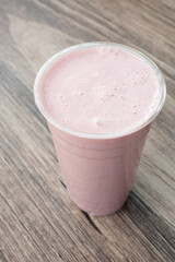 A view of a strawberry smoothie, in a plastic cup.