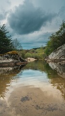 Obraz premium Serene landscape view of a calm river surrounded by trees, with dramatic clouds reflecting in the water.
