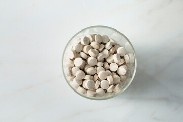 A top down view of a glass jar of pomegranate supplements.
