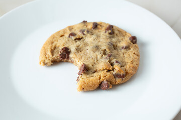 A closeup view of a chocolate chip cookie, featuring a bite mark.