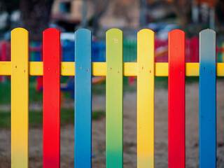 The colorful painted wooden boards on the fence around a playground are illuminated by the rays of the setting sun. Pula, Croatia - January 3, 2025