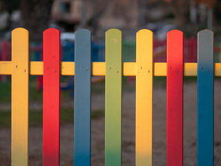 The colorful painted wooden boards on the fence around a playground are illuminated by the rays of the setting sun. Pula, Croatia - January 3, 2025