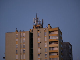 Cellular antennas and transmitters on roof of residential building. Radio transmitting equipment and communication lines on roof. 5G antennas. Evening sunset sky. Pula, Croatia - January 3, 2025