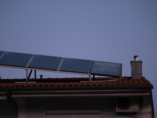 Solar panels installed above the tiled roof. Ventilation pipe with rotating nozzle. Solar energy concept. Pula, Croatia - January 3, 2025