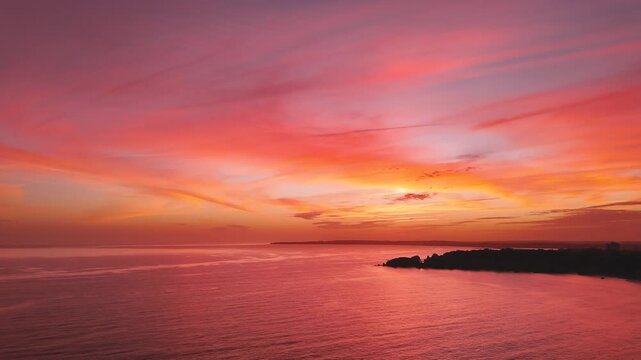 Aerial view of a stunning seascape during sunset with a sky dramatically painted in shades of orange, pink, and red in Algarve, PortugalAerial view of a stunning seascape during sunset with a sky dram