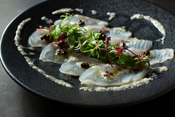 A closeup view of a whitefish carpaccio appetizer plate.
