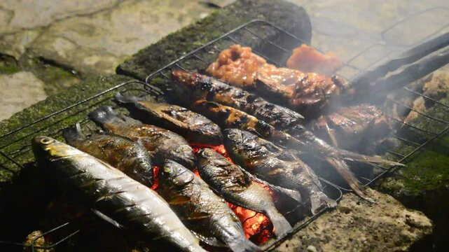 The traditional process of smoking grilled fish at night. Grilled fish smoking .