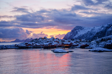 A breathtaking scenic winter sunset casts beautiful colors over a snowy village by the water