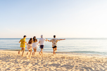 Happy man and woman travel the sea on summer beach holiday vacation. Group of Asian people friends enjoy and fun outdoor lifestyle travel nature running and playing together at tropical island beach.