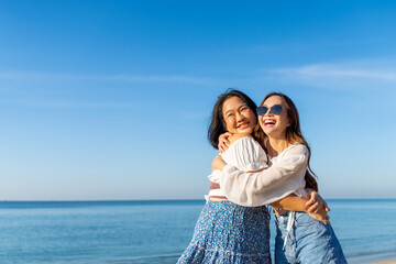 Happy woman travel nature ocean on summer beach holiday vacation. Portrait of Asian women friends enjoy and fun outdoor lifestyle hugging and playing during travel tropical island beach in sunny day.