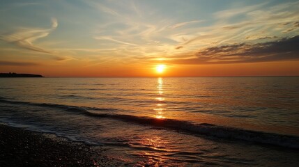 Serene summer sunset over calm sea reflecting golden hues on tranquil shoreline