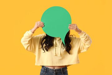 Young woman with blank speech bubble on yellow background