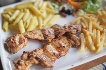 Grilled Chicken with Pasta, Fries, and Fresh Salad on a White Plate