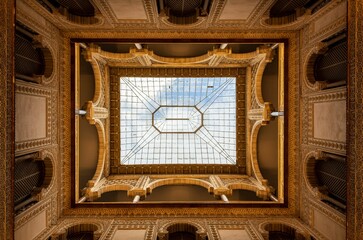 Intricate architectural ceiling view with ornate details and a glass skylight.