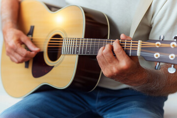 Fototapeta premium Person Playing Acoustic Guitar with Hands Close-Up in Natural Lighting