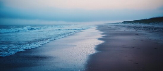 Naklejka premium A misty morning at the beach with the ocean waves crashing on the shore.