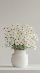 A bouquet of daisies in a white vase and a book on a white table.