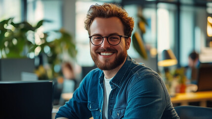 A man wearing glasses and a blue shirt is smiling