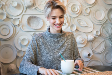 young beautiful woman sitting in a cafe and drinking coffee
