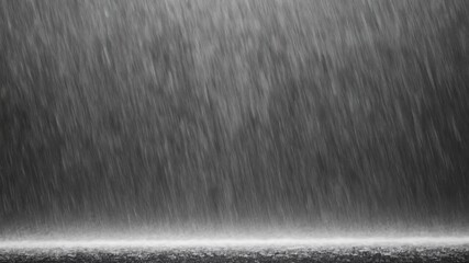 A dramatic scene of heavy rain falling in thick vertical streaks with a muted grayscale tone