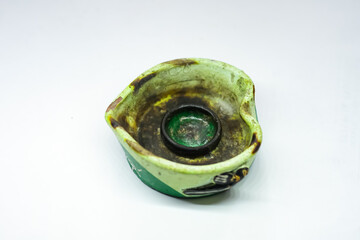 Photo of a green ashtray made from clay. The ashtray has been used so it has a black color due to cigarette ash.