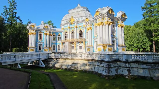 The Hermitage Pavilion in Catherine Park, Tsarskoye Selo, near Saint Petersburg, Russia. The ornate baroque architecture features blue and white walls with gold detailing, surrounded by greenery