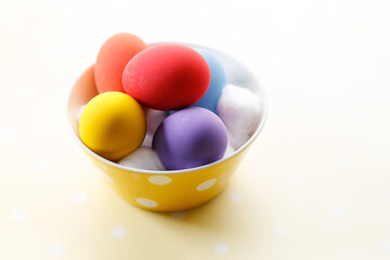 Happy Easter eggs in a bowl on dot yellow color background.