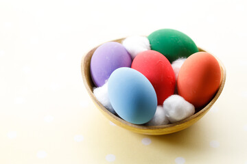 Happy Easter eggs in a bowl on dot yellow color background.