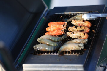Grilling food, shrimp on a stove. It makes the food taste a pleasant aroma, grilled shrimp cooking on the barbecue while sailing a yacht