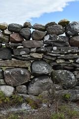 A rustic stone wall stands strong amidst green grass under a blu