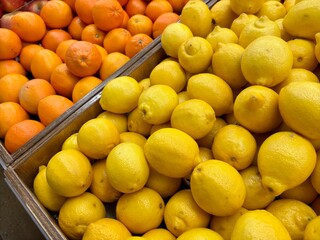 Closeup of fresh yellow lemons and vibrant oranges in wooden bins