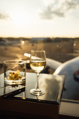 Photo of a glass of white wine and empty bourbon glass at airport