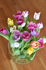 A vibrant bouquet of tulips in various colors fills a glass vase