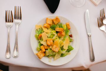 Caesar salad with croutons and parmesan on a white table setting