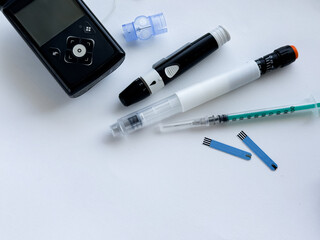 Diabetes management tools, insulin pen, glucometer, and test strips on white background