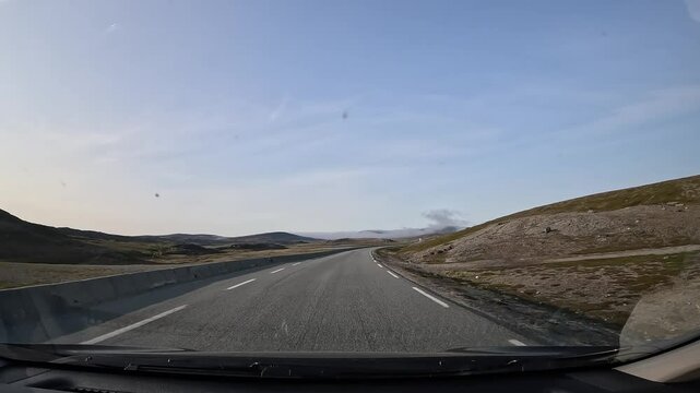 Driving through the tundra in northern Norway on E69 road. Rocky terrain covered with grass, moss, and lichens. A stunning road journey through breathtaking Arctic landscapes.